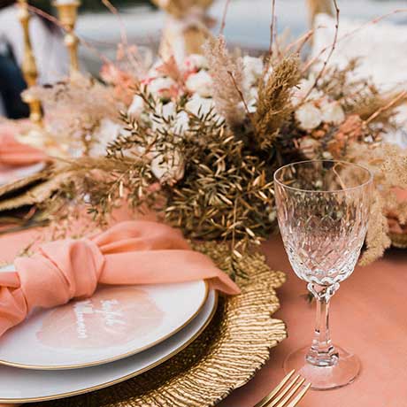 Gedeckter Platz mit Teller, Serviette, Glas und Trockenblumen